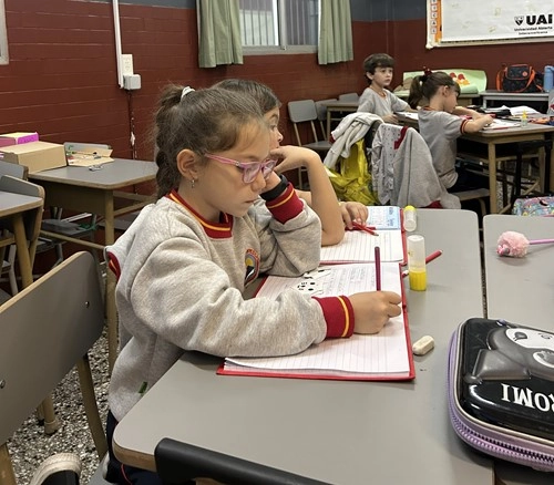 Alumna del Nivel Primario del Colegio Alberdi realizando actividades de escritura y aprendizaje en el aula.